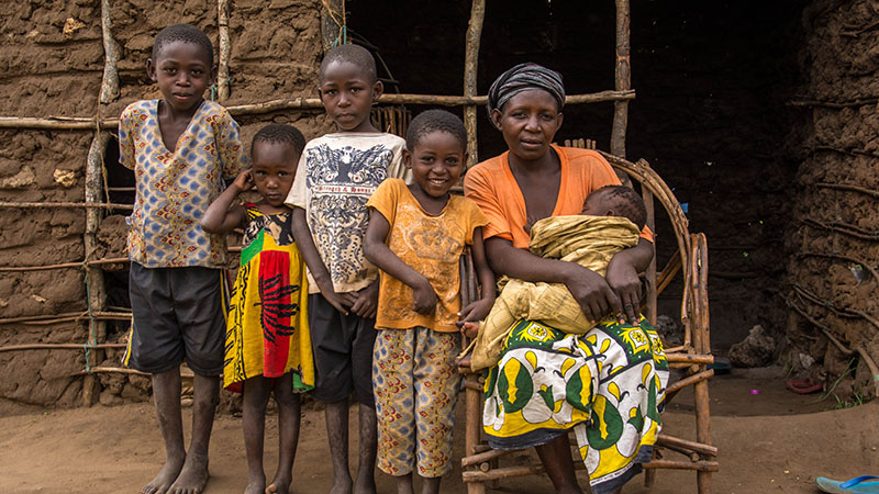 Moeder in Kenia met haar kinderen voor het huis. 