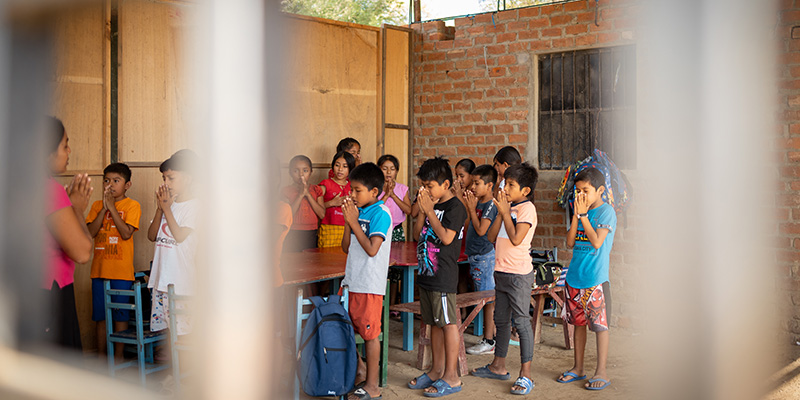 Een groep kinderen uit Peru bidt op het Compassion-project.