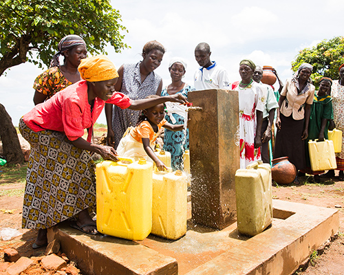 Ugandese moeder en dochter bij een waterpomp.