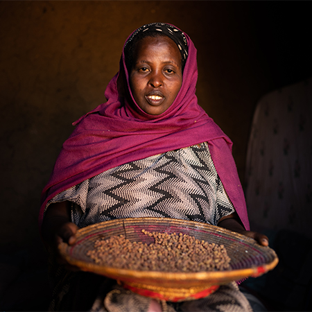Samiya uit Ethiopië zit met een mand met eten op schoot. 