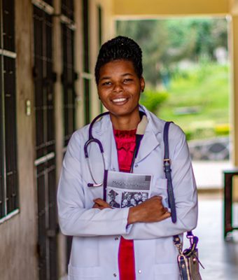 Flomena uit Tanzania studeert om dokter te worden en staat in haar doktersjas op de foto.