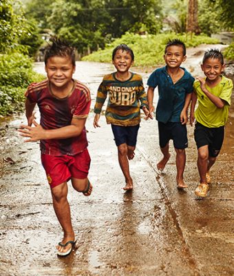 Rennende thaise kinderen in de regen.