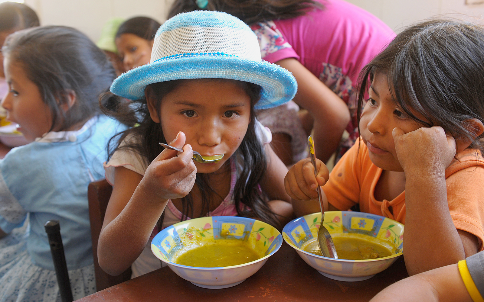 Boliviaans meisje eet soep uit een kom.