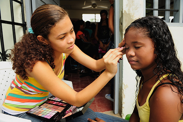 Twee Colombiaanse meisjes oefenen met make-up op elkaar.