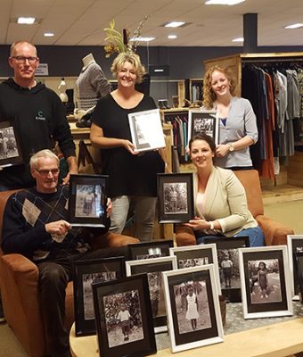 Medewerkers van Nobel kringloopwarenhuis met foto's van de kinderen die zij sponsoren.