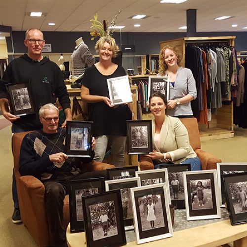 Medewerkers van Nobel kringloopwarenhuis met foto's van de kinderen die zij sponsoren.