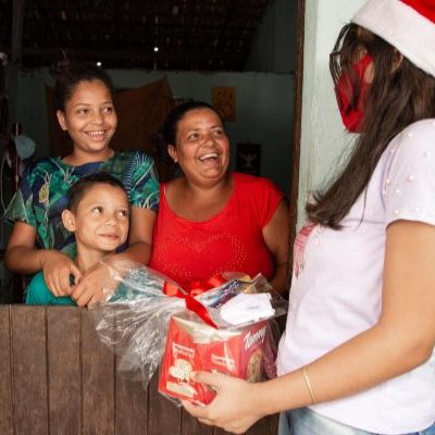 Een gezin in Brazilië ontvangt een kerstcadeau van een projectmedewerker.