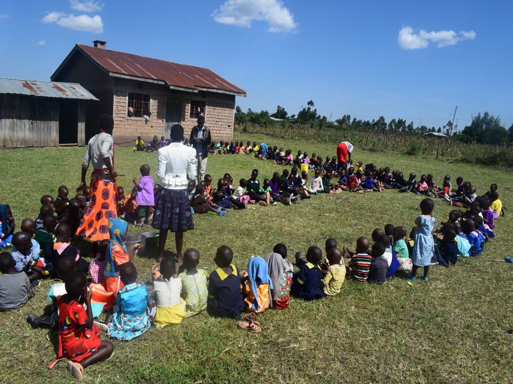 Kinderen zitten op het gras en krijgen onderwijs.