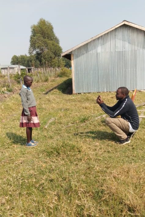 Een man maakt een portretfoto van een meisje voor de registratie in het Compassion-project.