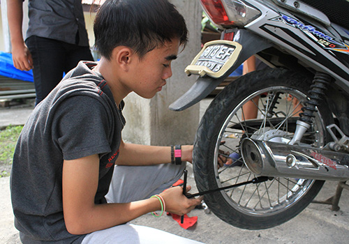 Indonesische jongen werkt aan brommer