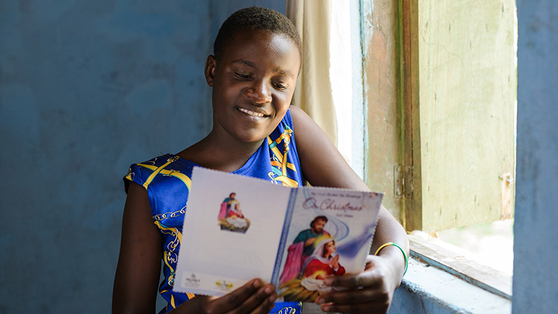 Brenda uit Uganda leest haar kerstkaart. 
