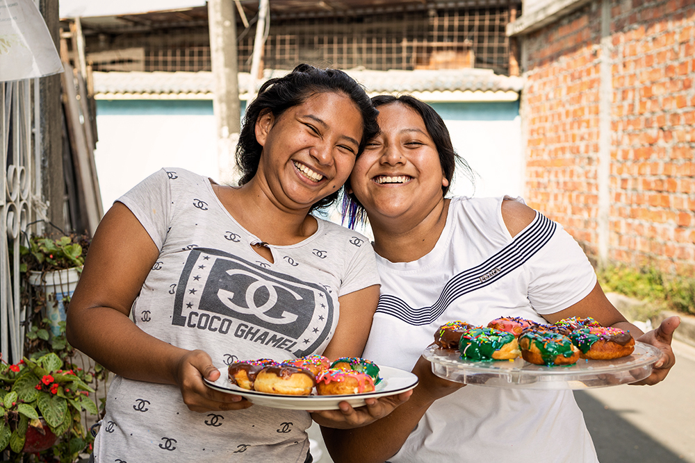 Noemi en Karen uit Ecuador laten hun zelfgebakken donuts zien.