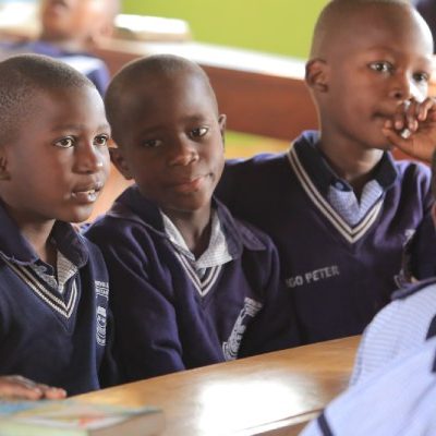 Drie jongens in Uganda zitten op school.