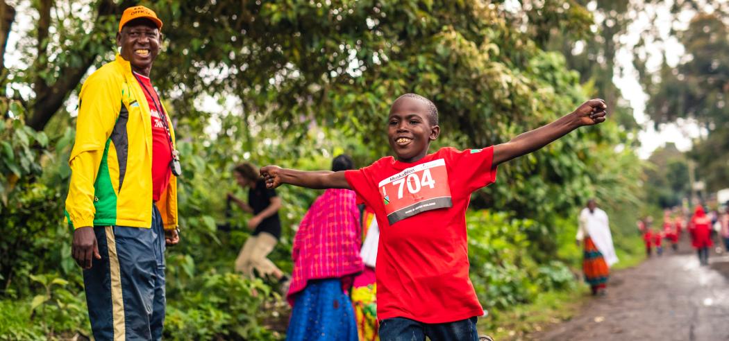 Een jongen uit Uganda rent over de finish tijdens de Muskathlon.