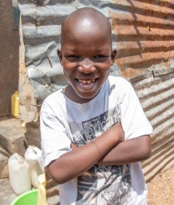 Jongen uit Uganda lacht in de camera.