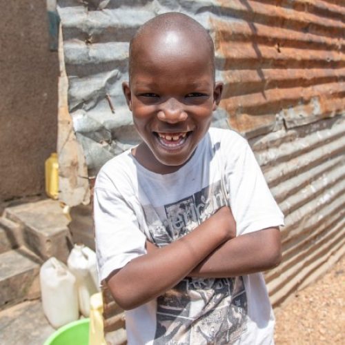 Jongen uit Uganda lacht in de camera.