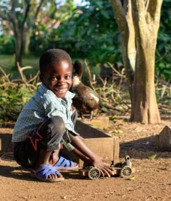 Jongen uit Uganda speelt met een zelfgemaakte speelgoedauto.