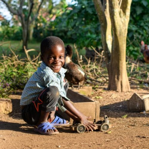 Jongen uit Uganda speelt met een zelfgemaakte speelgoedauto.
