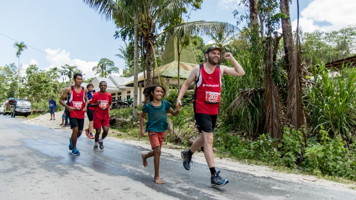 Man rent samen met een meisje over de weg tijdens de Muskathlon in Indonesië.