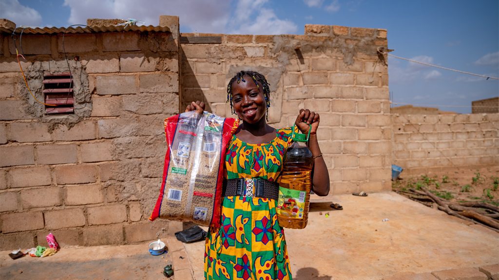 Wennefangdé uit Burkina Faso houdt een zak rijst en een fles olie vast die ze kreeg op het Compassion-project