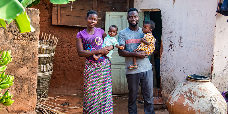 Moeder en vader uit Togo staan voor hun huis met hun dochters. 