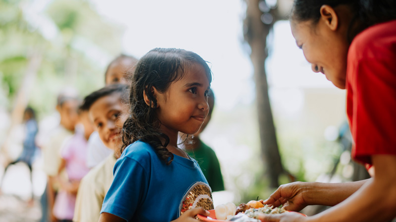 Een meisje krijgt een bord eten op een Compassion-project.