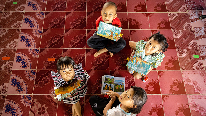 Kinderen uit Thailand zitten op de grond met hun kinderbijbel.
