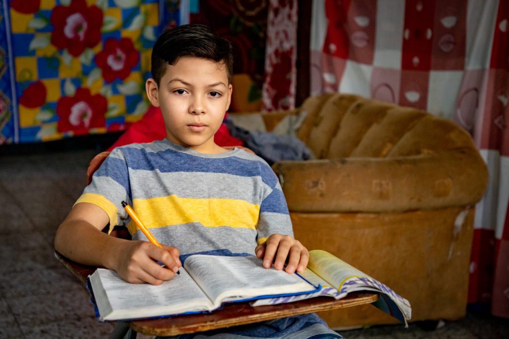 12-jarige Angel uit Honduras doet zijn huiswerk in het opvangcentrum.