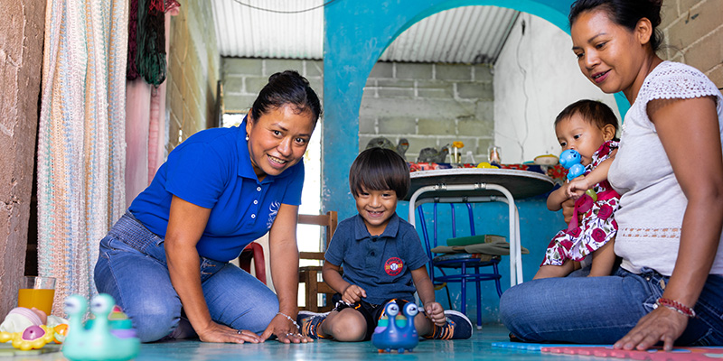 Projectmedewerker Antonia uit Mexico is op huisbezoek en speelt met de kinderen.