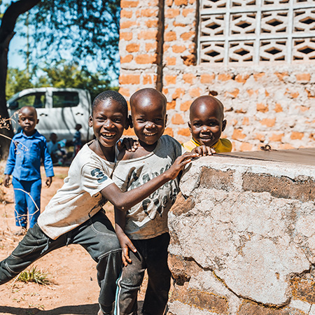 Drie lachende kinderen op een Compassion-project in Tanzania tijdens de Muskathlon.