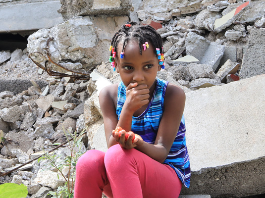 Soraya uit Haïti zit op de brokstukken van haar huis.