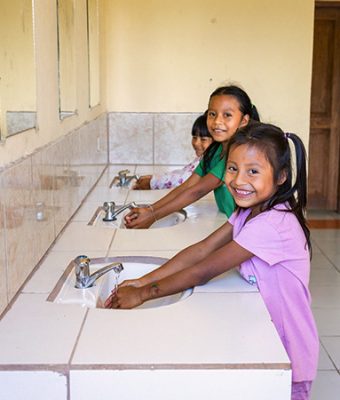 Kinderen uit Latijns-Amerika wassen hun handen bij nieuw gebouwde sanitaire voorzieningen