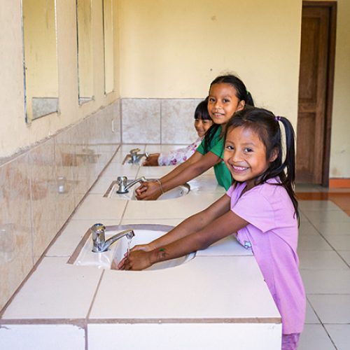 Kinderen uit Latijns-Amerika wassen hun handen bij nieuw gebouwde sanitaire voorzieningen