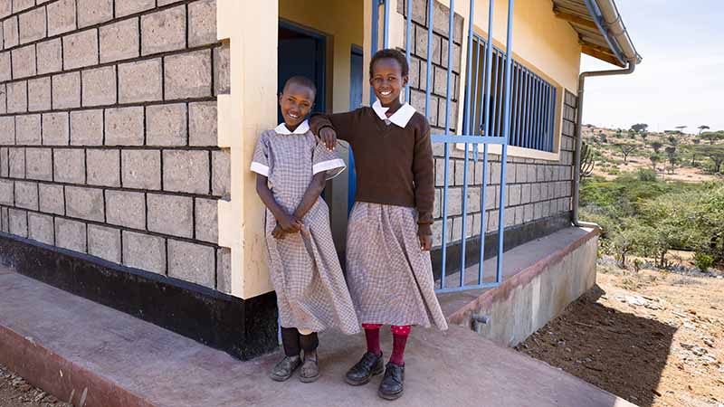Namunyak en Nasieku staan bij het nieuwe toiletgebouw in Doldol, Kenia.