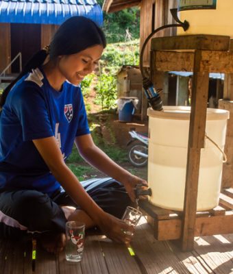 Vimala uit Thailand tapt water uit de nieuwe waterfilter bij haar huis.