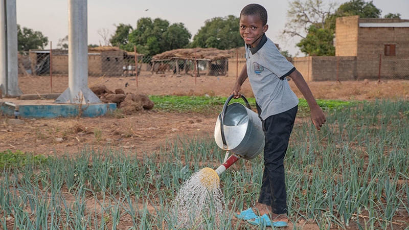 Fabrice uit Burkina Faso geeft de planten in de moestuin water. 