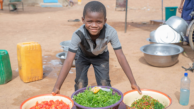 Fabrice uit Burkina Faso met verse groente uit de moestuin. 