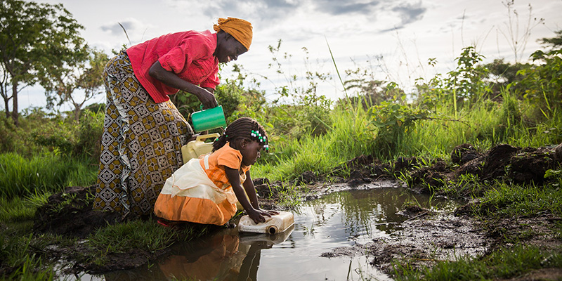 Betty en haar moeder Evelyn uit Uganda halen water uit een rivier.