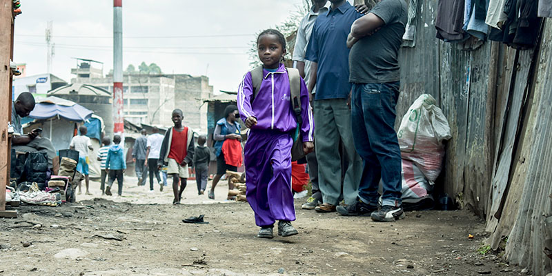 Een kind uit Kenia loopt door de sloppenwijk. 