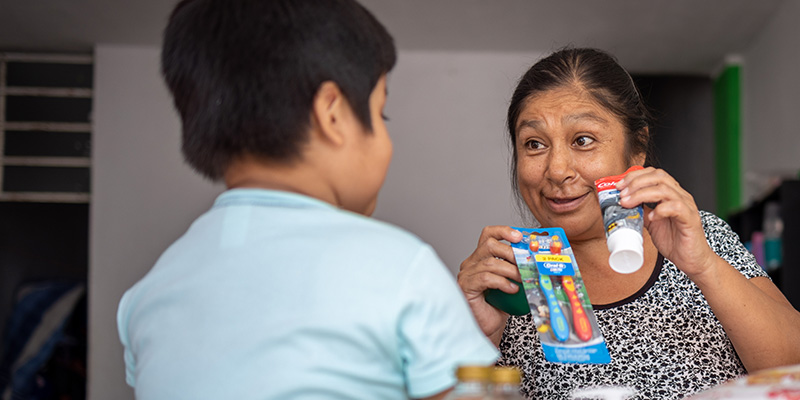 Oma Liliana laat tandpasta en een tandenborstel zien aan haar kleinzoon Raulito.