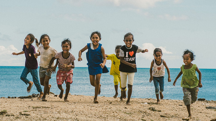 Aziatische kinderen rennen op het strand.