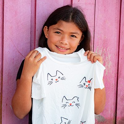 Een meisje houd een shirt met kattenprint omhoog.