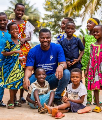 Koffi Ahonon, directeur van Compassion Togo, zit tussen kinderen uit een Compassion-project.