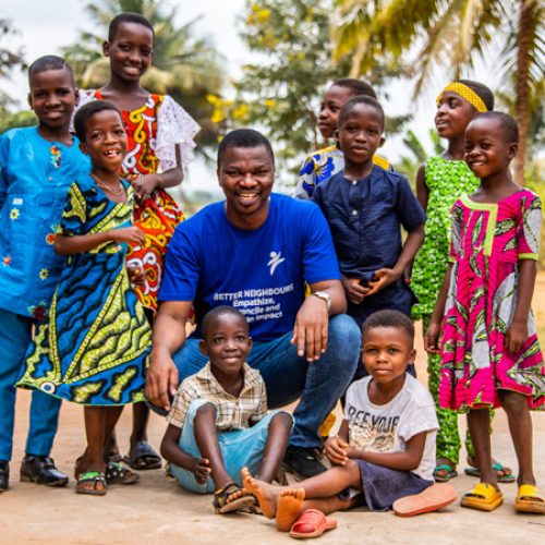 Koffi Ahonon, directeur van Compassion Togo, zit tussen kinderen uit een Compassion-project.