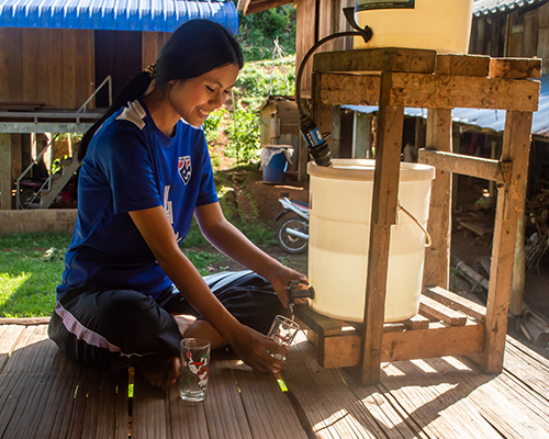 Vimala uit Thailand tapt water uit de nieuwe waterfilter bij haar huis.