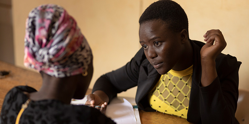 Kiiza uit Uganda zit aan tafel tegenover een vrouw. 