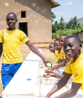 Een groep jongens wast hun handen op een Compassion-project in Rwanda.