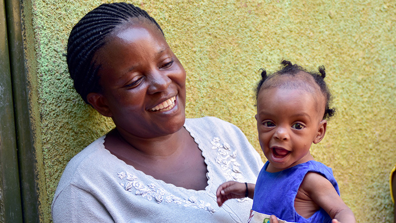 Moeder Gladys uit Uganda lacht naar haar baby Miracle.