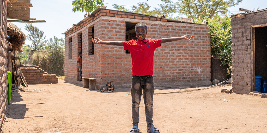 Tanzaniaanse jongen staat voor een nieuw gebouwd huis