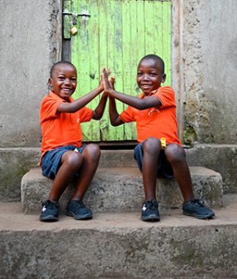 Twee jongens uit Rwanda geven elkaar een high five.